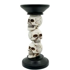 three skulls stacked on top of each other in a black vase with a white background