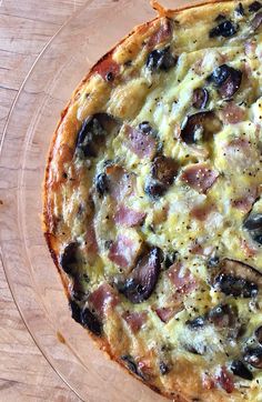 a pizza sitting on top of a glass plate covered in cheese and black olives