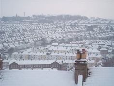 snow covered rooftops and buildings in a city with lots of houses on the horizon