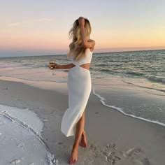 a woman standing on top of a beach next to the ocean