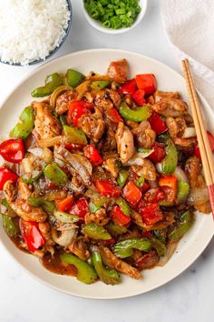 a white plate topped with chicken and peppers next to rice