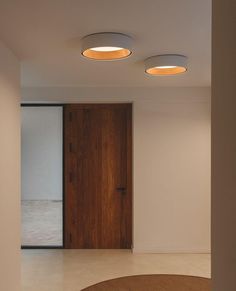 an empty room with two round lights on the ceiling and a door in the background