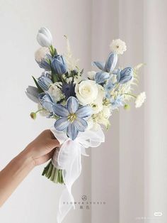 a person holding a bouquet of white and blue flowers