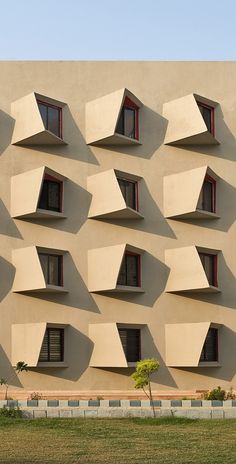 an unusual building with many windows on the side and grass in front of it that has been designed to look like hexagonal shapes