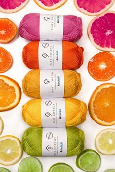 four skeins of yarn surrounded by citrus slices and oranges on a white surface