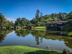 a lake surrounded by lush green trees in the middle of a park with pavilions