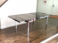 a glass table sitting on top of a hard wood floor next to a stair case