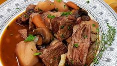 a white plate topped with meat and veggies covered in gravy on top of a wooden table