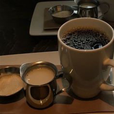 there is a cup of coffee on the table next to two measuring spoons and cups