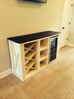 an entertainment center in the corner of a room with tile flooring and a flat screen tv mounted above it