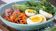 a blue bowl filled with vegetables and hard boiled eggs on top of it's sides