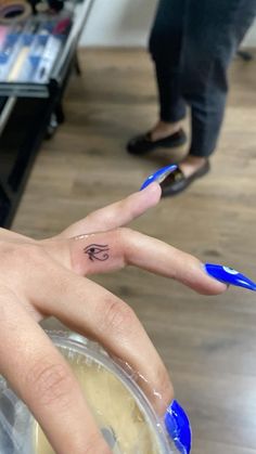 a woman's hand with a small tattoo on her left ring finger, in front of a store display