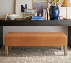 a brown bench sitting in front of a table with pictures and vases on it