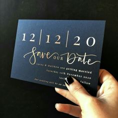 a hand holding up a black and gold save the date card with writing on it