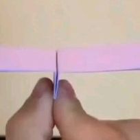 a person holding a piece of pink paper in their left hand with one end torn off