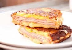 two ham and cheese grilled sandwiches on a white plate