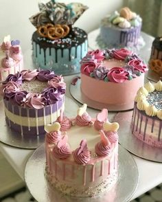 there are many different cakes on the table and one is pink, blue, purple and white