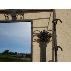 a mirror on the side of a building with an iron frame and flower decoration hanging from it