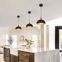 an open kitchen with marble counter tops and pendant lights hanging from the ceiling over the island