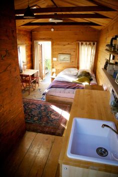 there is a kitchen and living room in this cabin with wood floors, exposed beams, and wooden walls