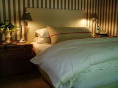 a bed with two lamps on either side of the headboard and one night stand