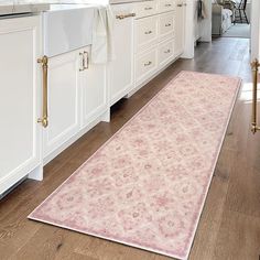 a pink rug is in the middle of a kitchen with white cabinets and counter tops