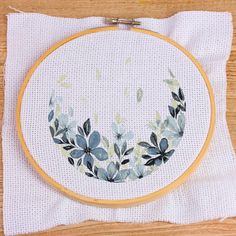 a cross - stitch pattern with leaves on it sitting on top of a piece of cloth