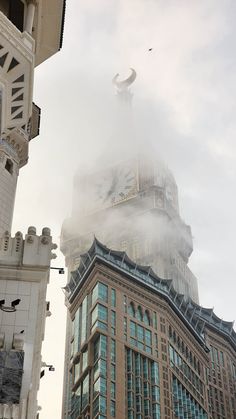 a large building with a clock on it's face in the foggy sky