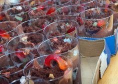 many desserts are in plastic cups on the table