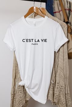 C'est La Vie Paris T-Shirt, Gift For Paris Lover, Parisian Gift, Paris Girl, Paris Vacation, French Gift, Gift for Paris Trip, France Trip Tee. Super soft Bella Canvas 3001 shirt.  Bella+Canvas® 3001 *Best Seller* 100% No Sweatshops & Eco-Friendly  Adult Unisex Sizing; Classic Fit 100% Airlume Combed & Ring-Spun Cotton 4.2oz Solids Colors: 100% Airlume Combed & Ring-Spun Cotton 4.2oz Heather Colors: 52% Airlume Combed & Ring-Spun Cotton, 48% Polyester 4.2 oz.  Athletic Heather & Black Heather: 90% Airlume Combed and Ring-Spun Cotton, 10% Polyester 4.2 oz.  💦 CARE * Wash INSIDE OUT for the best care, with like colors * Machine wash COLD. Tumble dry. Do not iron directly on design; Do not dry-clean. Hang Dry recommended. 📐SIZING * Please reference the sizing chart and fit guide listed in t Paris Tee, France Trip, French Gifts, Paris Girl, Paris Vacation, Paris Trip, Travel Tees, Paris T Shirt, Emily In Paris