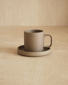 a cup and saucer sitting on top of a wooden table next to each other