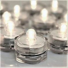 several clear jars with lit candles in the middle on a white table top, surrounded by smaller ones