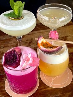 three different types of cocktails sitting on top of a wooden table next to each other