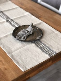 an empty plate sitting on top of a wooden table next to a white and black napkin