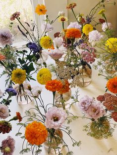 many different colored flowers in vases on a table