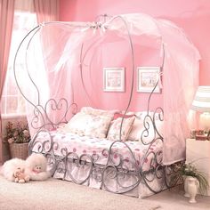 a pink bedroom with a canopy bed and two cats laying on the floor next to it