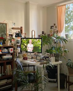 a computer monitor sitting on top of a desk next to a potted plant in front of a window