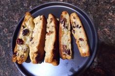 four pieces of bread sitting on top of a black plate with cranberry toppings