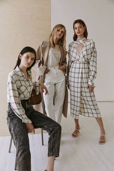 three models pose for the camera in white outfits and plaid shirts, with one woman sitting on a chair