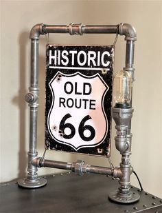 an old route 66 sign mounted to the side of a metal shelf next to a lamp