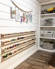 toy cars are lined up on shelves in a playroom with white walls and wood flooring