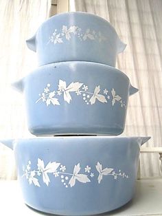 three blue casserole dishes stacked on top of each other in front of a window