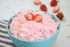 a blue bowl filled with strawberry fluff and topped with two strawberries