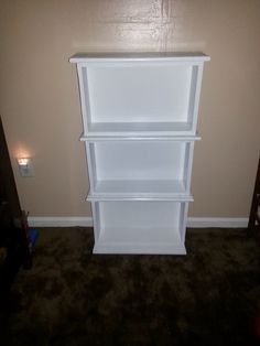 a white book shelf sitting in the corner of a room