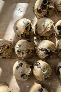 chocolate chip cookie doughnuts are arranged on a sheet of parchment paper, with one broken in half