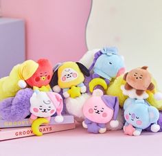 a group of stuffed animals sitting next to each other on a pink surface with a white background