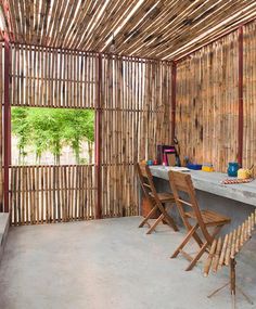 a table and chairs in a room with bamboo walls on the wall, windows to the outside