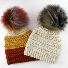 two knitted hats with pom - poms on them