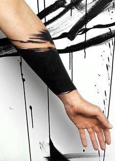 a person's arm with black ink on it and dripping paint all over the arm