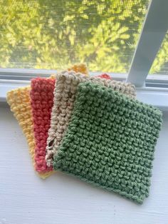 three crocheted dishcloths sitting next to each other on a window sill